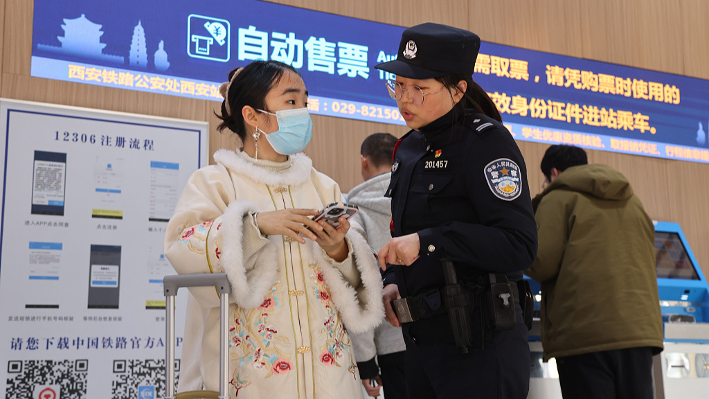 Passenger consults a local policewoman for railway ticket purchase at Xi'an Railway Station, Xi'an City, northwest China's Shaanxi Province, January 12, 2024. /CFP 