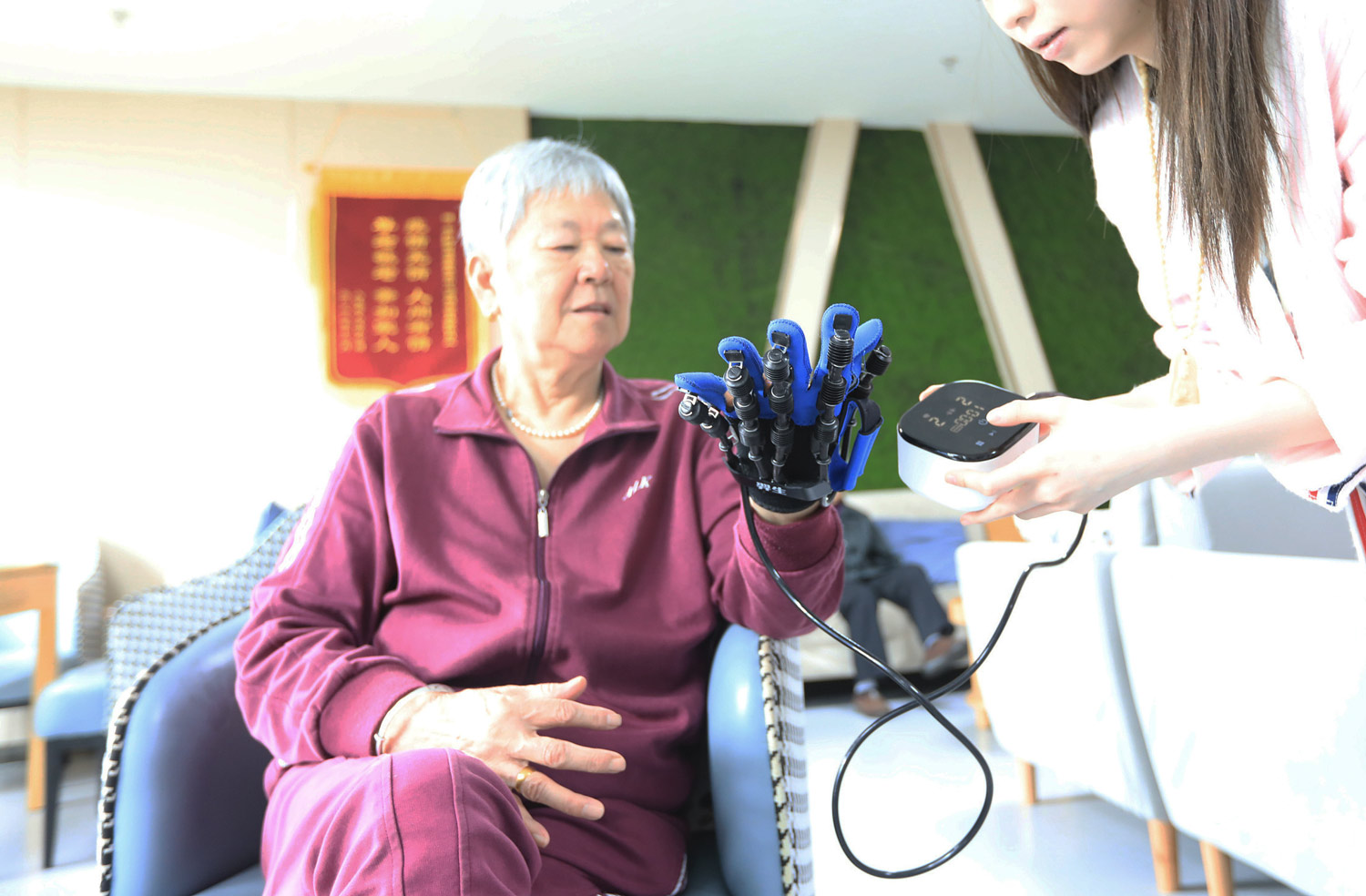 A woman tries out a device designed to assist seniors with hand mobility at a nursing home in Zhengzhou, Henan Province, April 20, 2023. /VCG